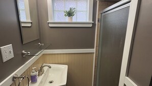 Baño con lavabo, espejo, ventana y ducha.