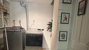 A compact kitchen with a refrigerator, stove, and sink. There is a small dining area with a chair and a table.