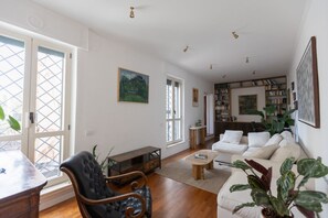 A spacious living room with a sofa, armchair, coffee table, and bookshelf. - GuestHost - Classy Apartment in Termini with Terrace (Rome)