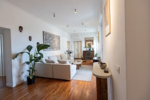 A modern living room with a sofa, coffee table, and potted plants. - GuestHost - Classy Apartment in Termini with Terrace (Rome)