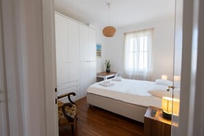 A hotel room with a bed, bedside table, lamp, and a wardrobe. - GuestHost - Classy Apartment in Termini with Terrace (Rome)