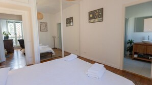 Ein Hotelzimmer mit einem großen Bett, einem Spiegel, Holzboden und einem Badezimmer mit Waschbecken und Spiegel.