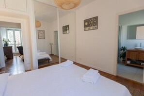 Ein Hotelzimmer mit einem großen Bett, einem Spiegel, Holzboden und einem Badezimmer mit Waschbecken und Spiegel.