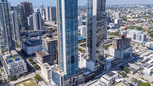 Un edificio de gran altura con fachada de vidrio moderna, rodeado de otros edificios altos en un entorno urbano.