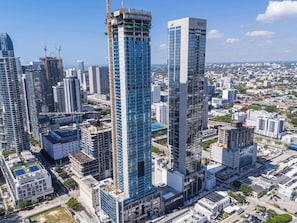 Ein Hochhaus mit moderner Glasfassade, umgeben von weiteren Hochhäusern in einer urbanen Umgebung.