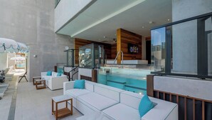 Un espacio lounge moderno al aire libre con piscina, asientos y vistas a la ciudad.