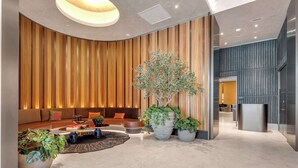 Un interior moderno con una zona de estar curvada, una gran planta en maceta y un elegante mostrador de recepción.