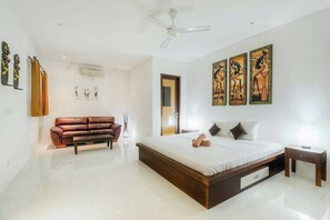 Un dormitorio moderno con una cama grande, un sofá de cuero marrón y tres cuadros en la pared.