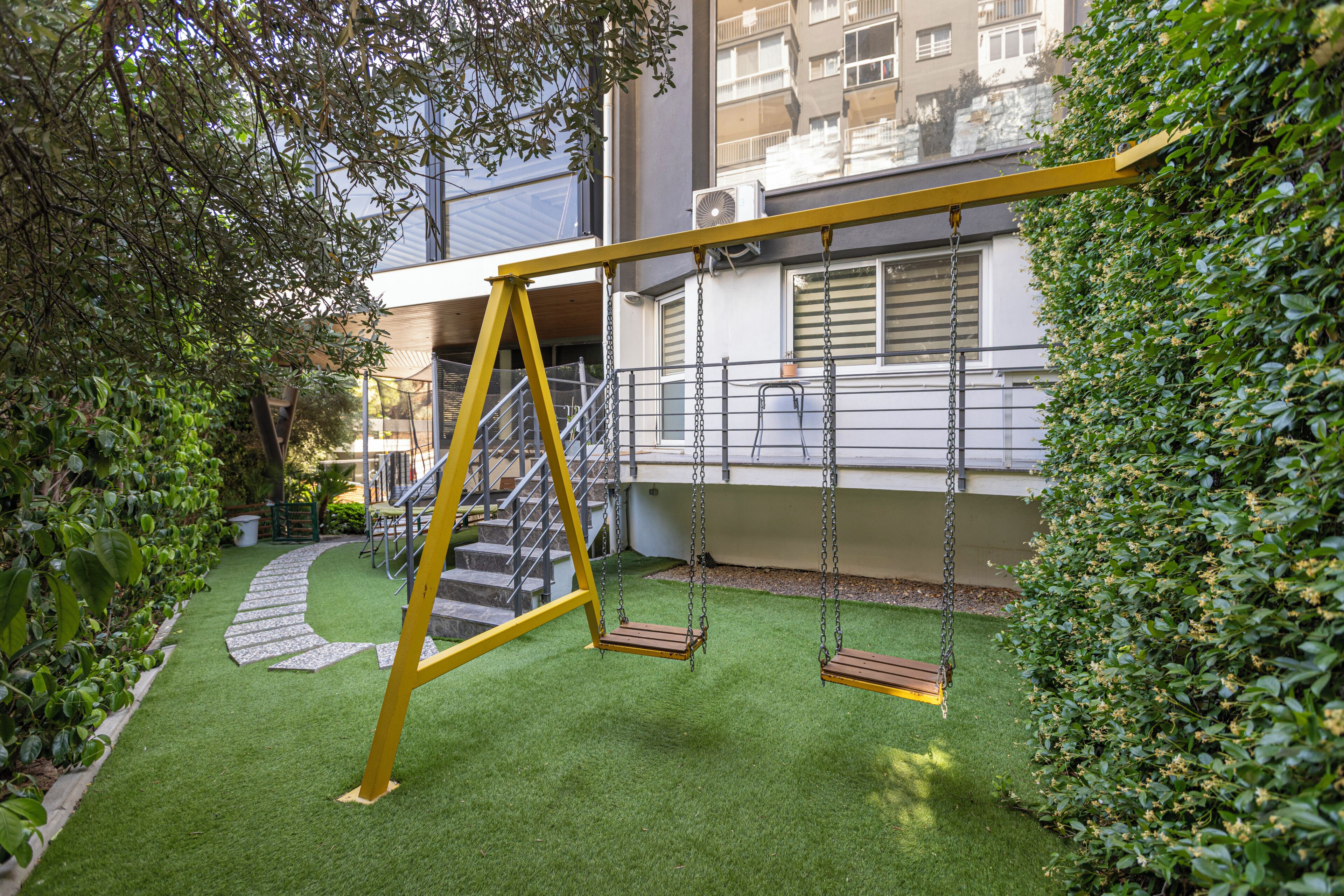 A playground with swings and a staircase leading to a building.