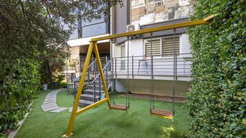 A playground with swings and a staircase leading to a building.