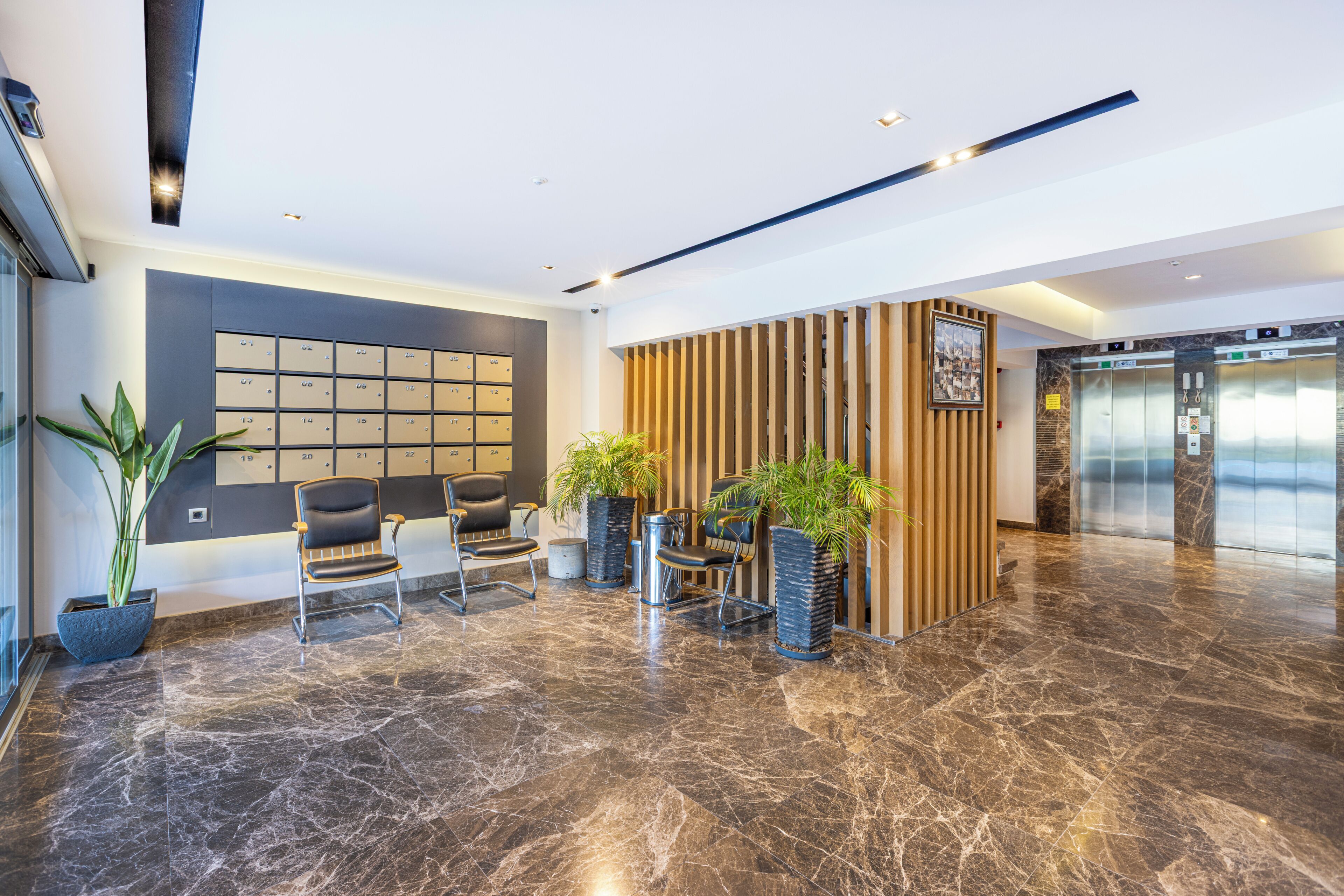 A modern lobby with a marble floor, seating area, reception desk, and an elevator.
