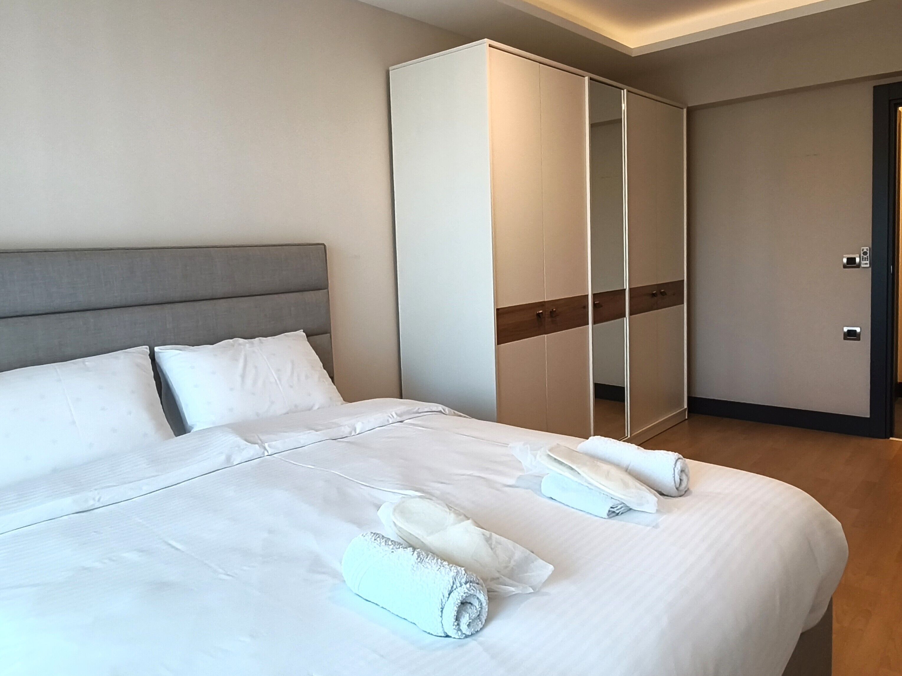 A hotel room with a large bed, a wardrobe, and a door.