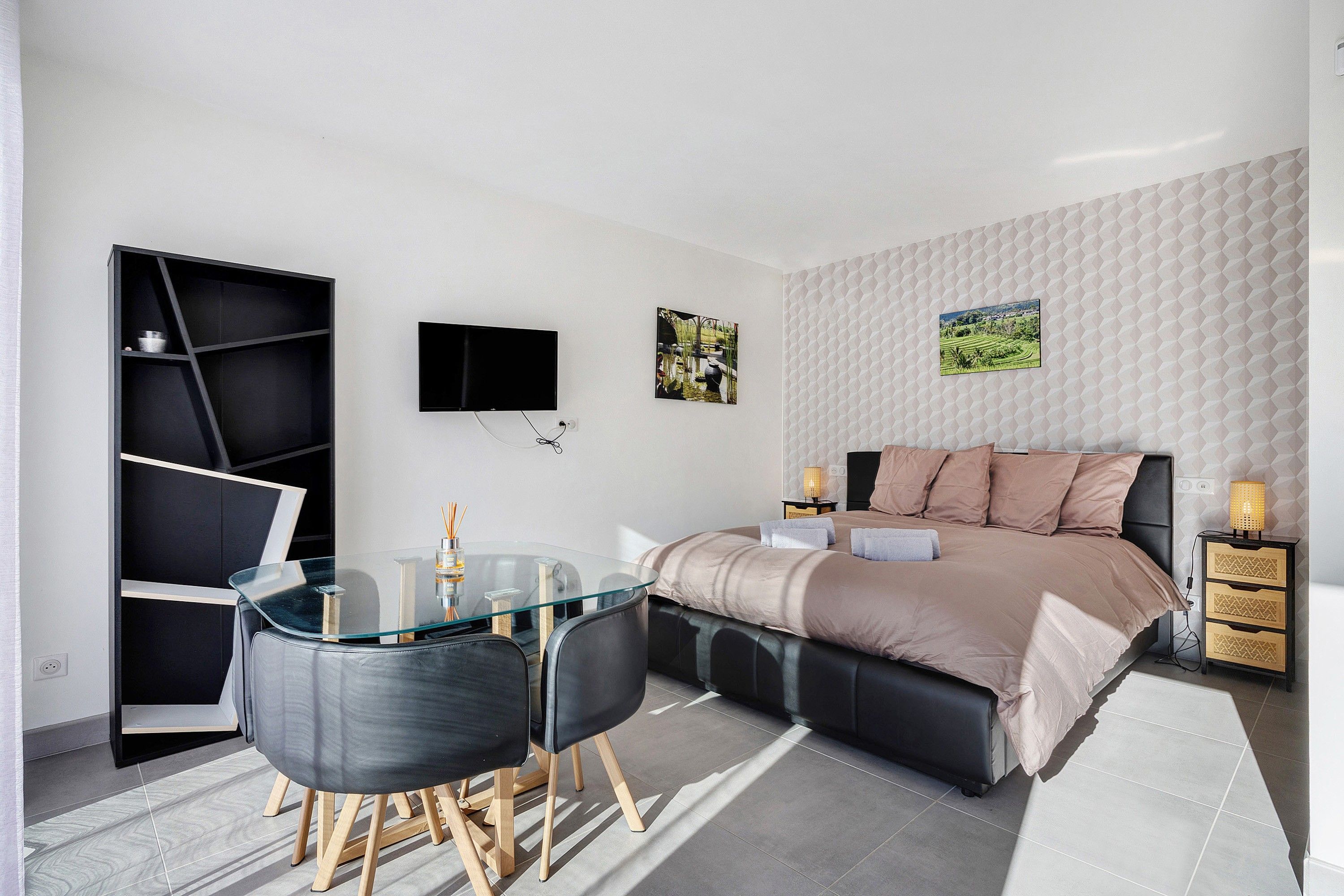 Une chambre moderne comprenant un lit, des tables de chevet, un téléviseur et un bureau avec des chaises.