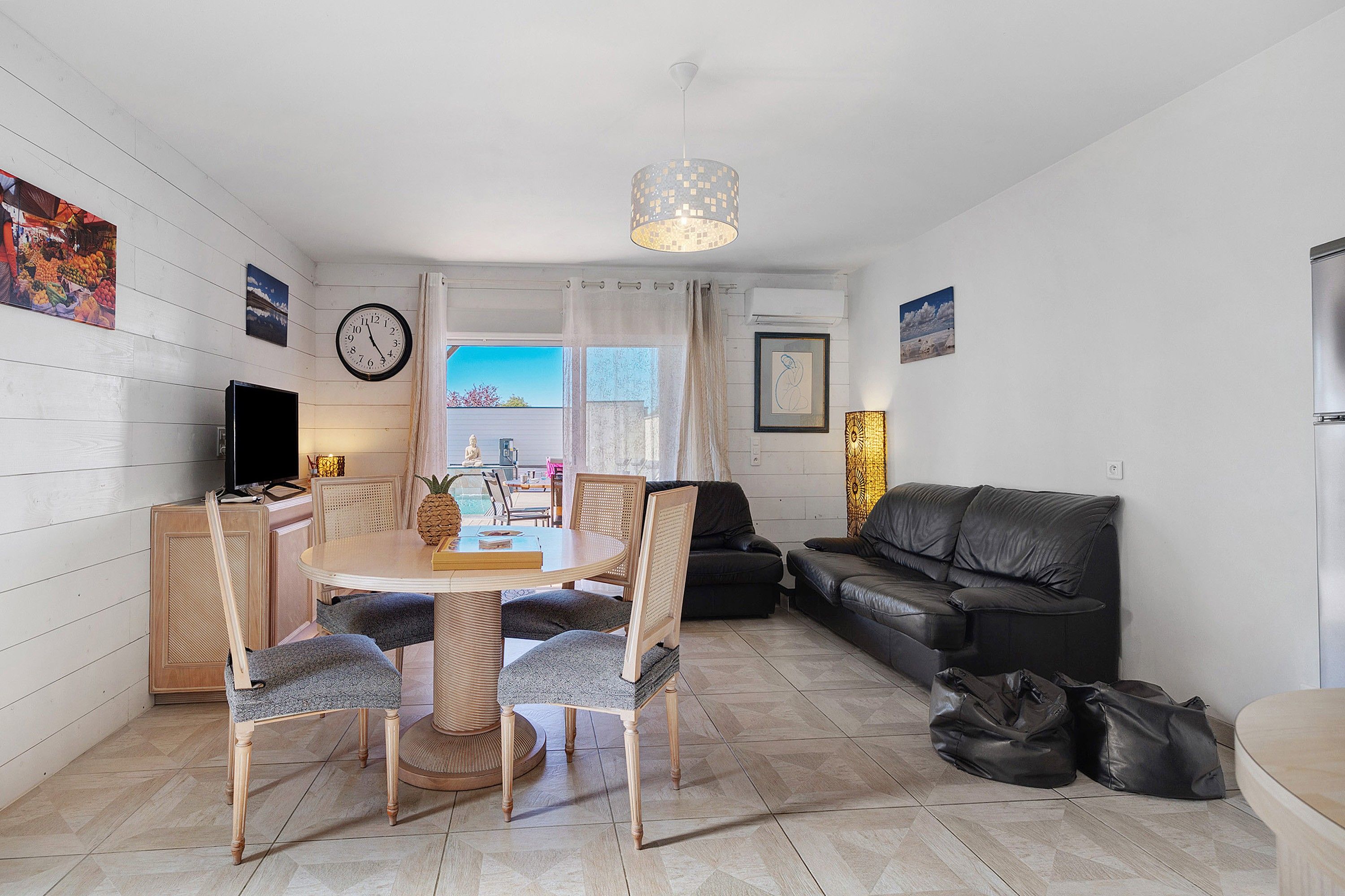Un salon comprenant un coin repas, un canapé en cuir noir et une table à manger avec des chaises.