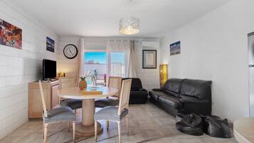 Un salon comprenant un coin repas, un canapé en cuir noir et une table à manger avec des chaises.