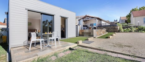 A modern house with a patio area featuring a table and chairs.