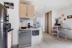 Eine moderne Küche mit Geschirrspüler, Kaffeemaschine und einem Essbereich mit Stuhl und Tisch.