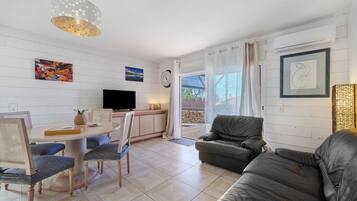 A modern living room with a dining area, a television, and artwork on the walls.