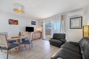 A modern living room with a dining area, a television, and artwork on the walls.