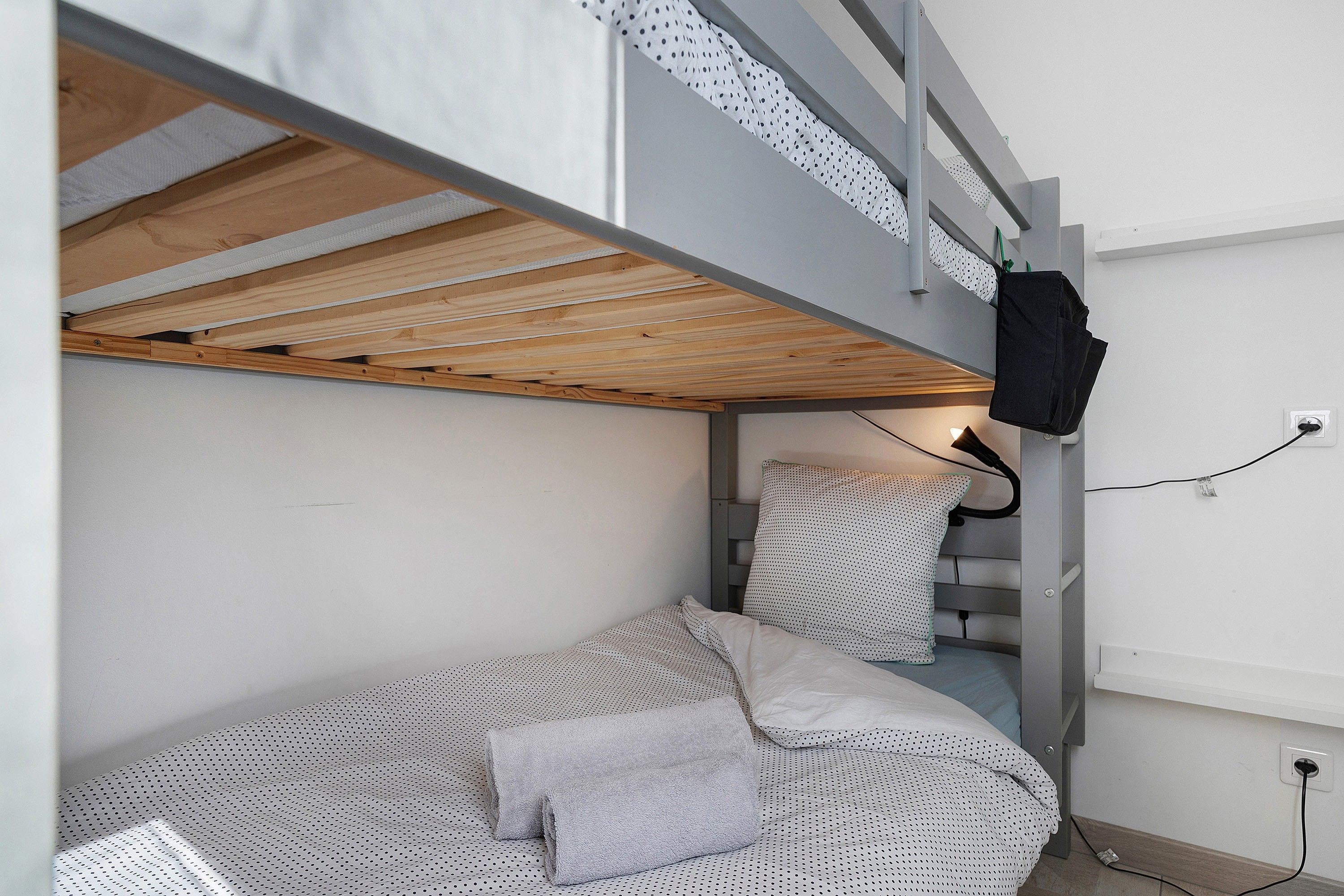 Uma cama beliche com cabeceira de madeira, um travesseiro e um cobertor estampado em bolinhas.