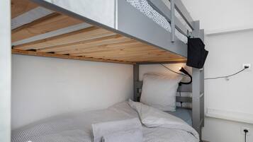 Uma cama beliche com cabeceira de madeira, um travesseiro e um cobertor estampado em bolinhas.