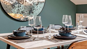 A dining table set with blue bowls, wine glasses, and plates, with a large abstract painting on the wall behind. - Host & Stay | The Georgian Quarter @ Catharine V (Liverpool)