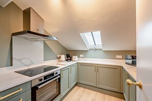 Een kleine keuken met een ingebouwde kookplaat, oven en dakraam.