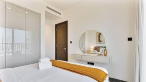 Habitación de hotel con cama, armario, espejo y mesita de noche.