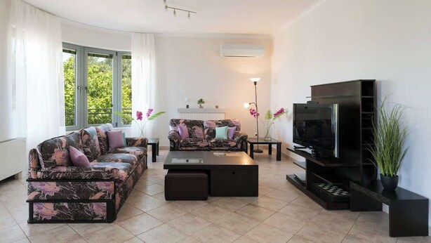 A modern living room with a sofa, a coffee table, a TV stand, and a fireplace. - Solena - Garden Escape with Views near Chania (Tsikalaria)
