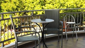 A balcony with wicker chairs and a small round table, overlooking a well-maintained hedge. - Solena - Garden Escape with Views near Chania (Tsikalaria)