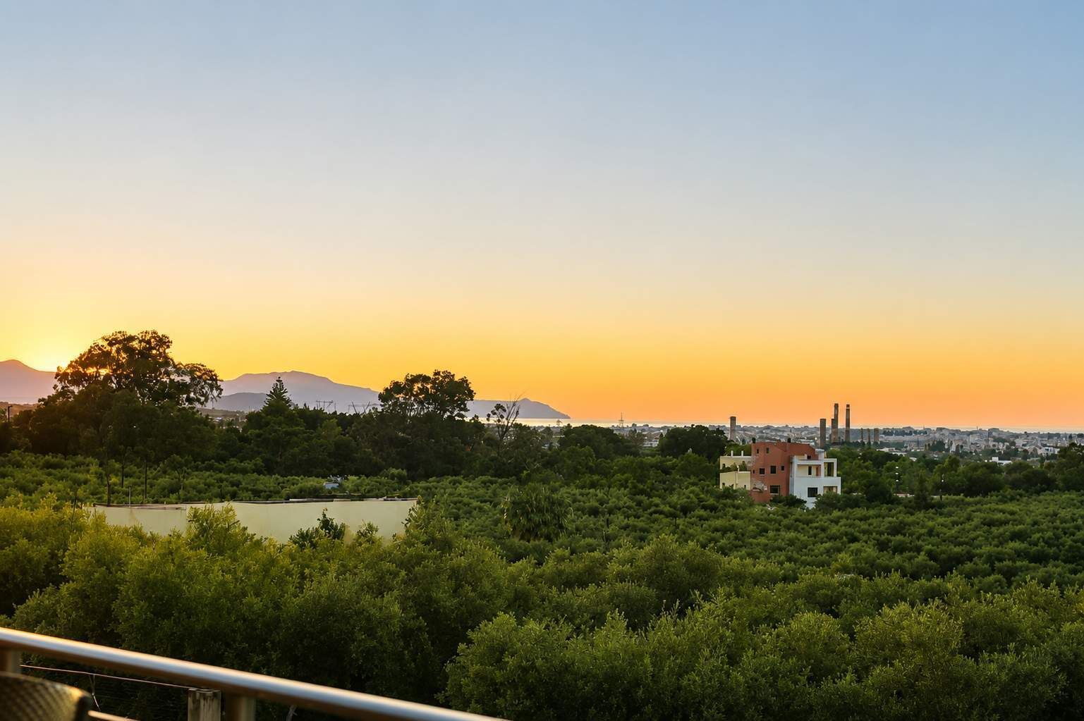 A landscape with a body of water, trees, and buildings in the distance.