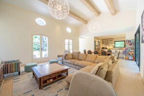 Ein geräumiges Wohnzimmer mit einer großen Couch, einem Holz-Couchtisch und einem Essbereich mit rundem Tisch und Stühlen.
