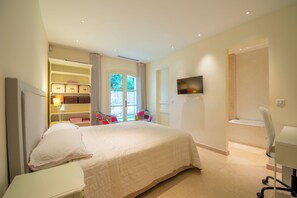 A bedroom with a bed, a desk, a chair, a TV, and a wardrobe. - Exceptional country house, Pampelonne and Club 55 just a 3-minute walk away - Pool - Ocean (ramatuelle)