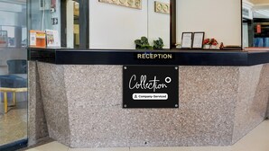Een receptiebalie met een bord waarop 'Collection' en 'Company-Serviced' staan.