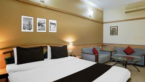 Een hotelkamer met een bed, een bank, een bijzettafeltje en kunstwerken aan de muur.