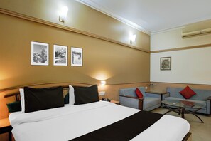 Ein Hotelzimmer mit einem Bett, einer Couch, einem kleinen Tisch und Wandbildern.