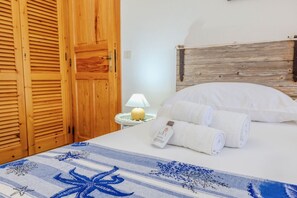 Een slaapkamer met een bed, nachtkastje, lamp en een houten kledingkast.
