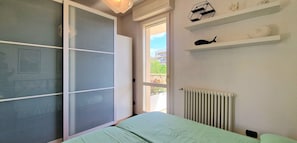 A bedroom with a bed, a sliding door, a radiator, and decorative items on the wall. - City / Village Apartment in Viareggio with 2 bedrooms sleeps 4 (Viareggio)