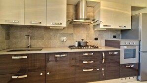 Een moderne keuken met donkere houten kasten, roestvrijstalen apparatuur en een gasfornuis.