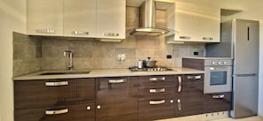A modern kitchen with dark wood cabinets, stainless steel appliances, and a gas stove. - City / Village Apartment in Viareggio with 2 bedrooms sleeps 4 (Viareggio)