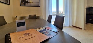 A conference room with a table, chairs, a radiator, a window with curtains, and a framed picture on the wall. - City / Village Apartment in Viareggio with 2 bedrooms sleeps 4 (Viareggio)