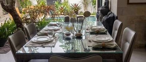 A dining area with a glass table, chairs, and a Buddha statue.