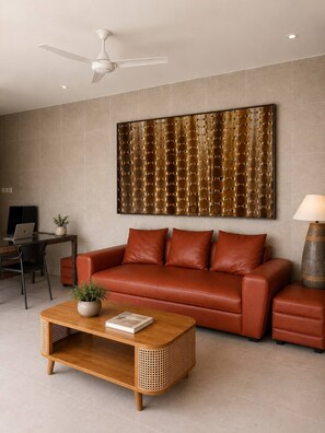 Ein modernes Wohnzimmer mit einem Ledersofa, einem Holztisch, einem Wandbild und einem Deckenventilator.