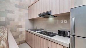 A modern kitchen with wooden cabinets, a stainless steel refrigerator, a gas stove, and a toaster. - Villa La Casa Ayana Canggu Berawa (Canggu)