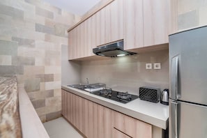 Eine moderne Küche mit Holzschränken, einem Edelstahlkühlschrank, einem Gasherd und einem Toaster.