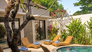 A poolside area with lounge chairs and a tree. - Villa La Casa Ayana Canggu Berawa (Canggu)