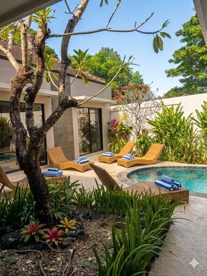 Ein Poolbereich mit Liegestühlen und einem Baum.