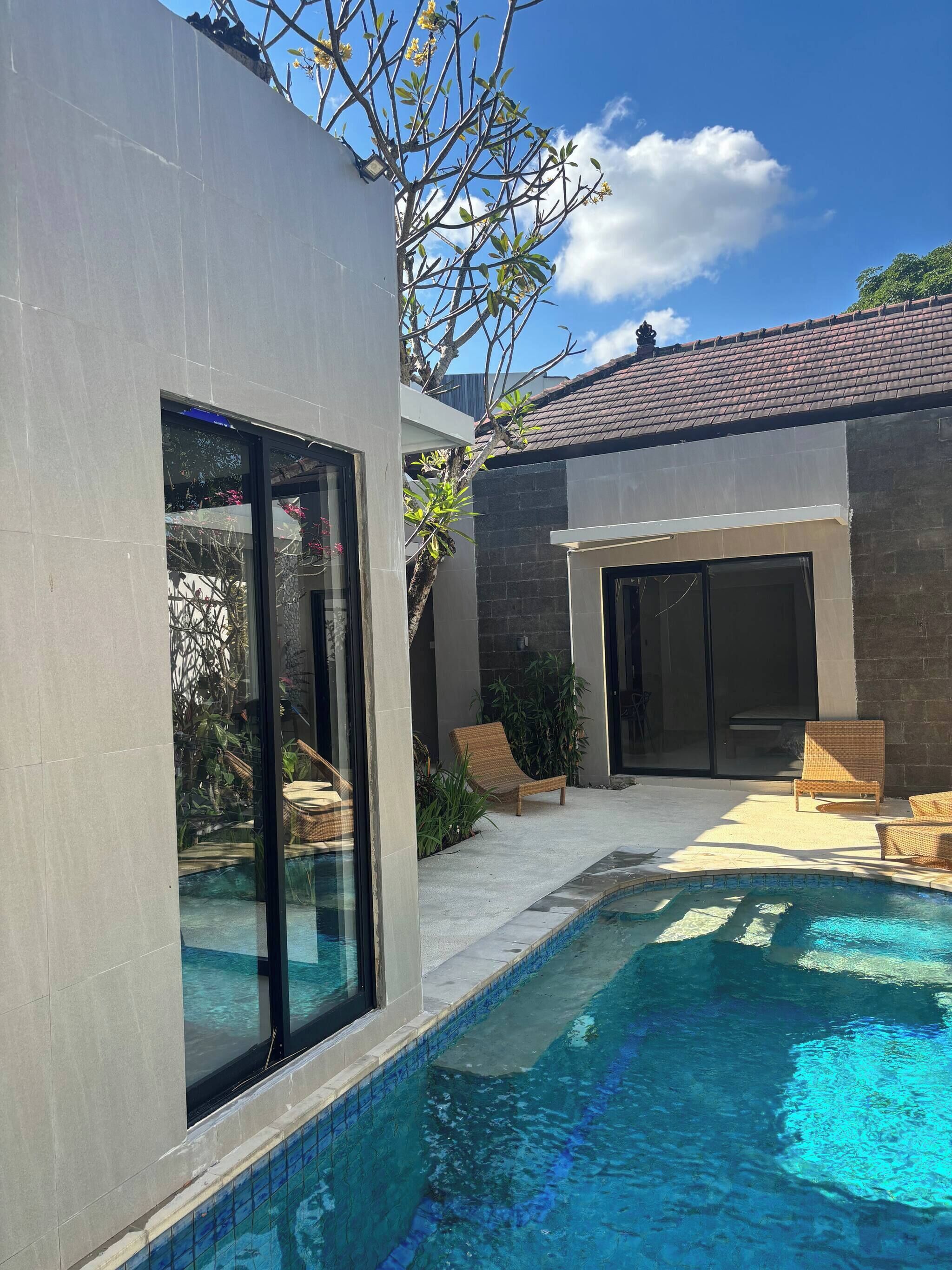 A modern house with a swimming pool, large windows, and outdoor seating.