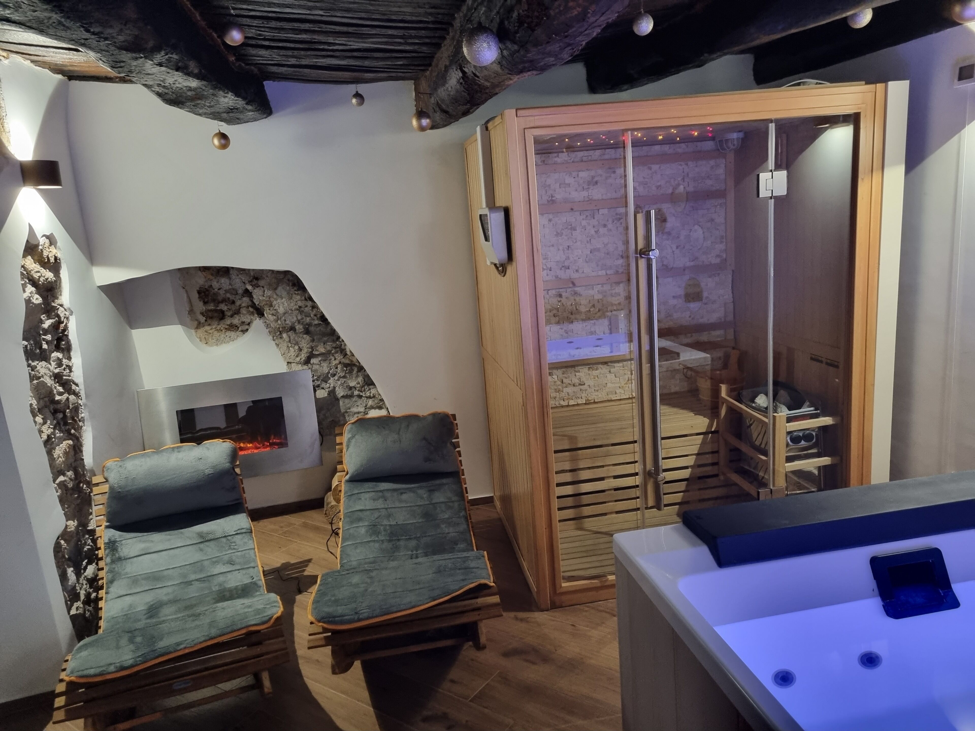 A spa room with two massage chairs, a sauna, and a wooden bench.