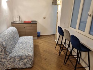 A compact living space with a sofa, a small kitchenette, and a dining area with bar stools. - Petramare Charming House: an oasis of wellness and relaxation with a spa in the heart of Salerno (SALERNO)
